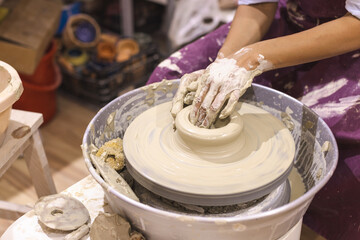 Pottery workshop. Closeup of woman artist hands molding clay on pottery wheel. Creative handmade craft. Ceramic studio.