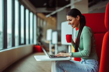 Joyful adult woman, drinking her morning coffee, at the office.