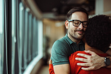 Calm caucasian man with glasses, enjoying the hug with his african-american friend. - obrazy, fototapety, plakaty