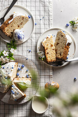 Easter composition with sliced cake, flowers and eggs on a light background with checkered tablecloth