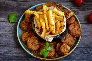 Home made  oven baked meatballs  from  chicken and vegetables and french potato  fries on  wooden background.Bifteki, or spicy meatballs 