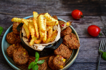 Home made  oven baked meatballs  from  chicken and vegetables and french potato  fries on  wooden background.Bifteki, or spicy meatballs 