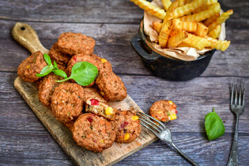 Home made  oven baked meatballs  from  chicken and vegetables and french potato  fries on  wooden background.Bifteki, or spicy meatballs 