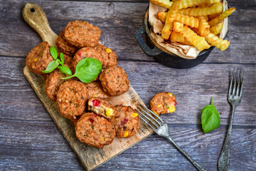 Home made  oven baked meatballs  from  chicken and vegetables and french potato  fries on  wooden background.Bifteki, or spicy meatballs 