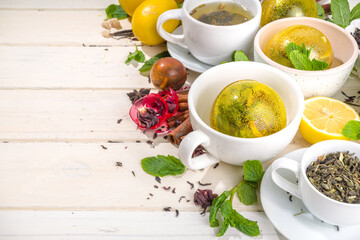 Various tea ball bombs. Assortment of different tea balls with dried tea, cups, lemon and mint, top view copy space. Trendy modern tea variety