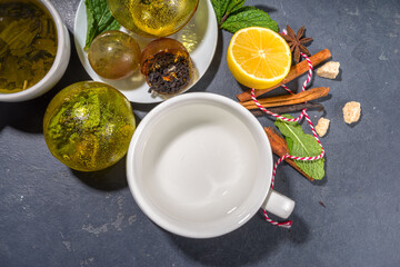 Making tea with Trendy modern tea ball bombs. Tea balls with dried tea, cups, lemon and mint, with classic white cup, top view copy space