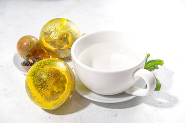 Making tea with Trendy modern tea ball bombs. Tea balls with dried tea, cups, lemon and mint, with classic white cup, top view copy space