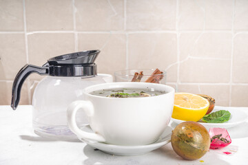Making tea with Trendy modern tea ball bombs. Tea balls with dried tea, cups, lemon and mint, with classic white cup, top view copy space