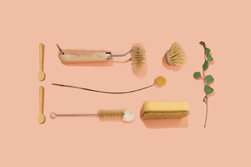 Set of eco friendly zero waste sustainable recyclable cleaning brushes and accessories with green eucalyptus and yellow flower ball on pink background. Alternative household chores. Natural living.