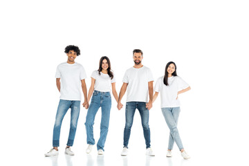 Obraz premium full length view of joyful interracial men and women holding hands while standing on white.