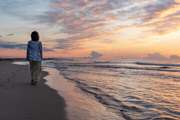 Woman walking at sunrise on the Beach of Platjola-Delta del Ebro