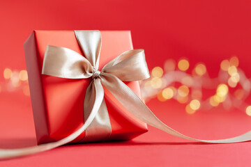 Red gift box with bow on red background. Happy Birthday or Valentine's Day concept.