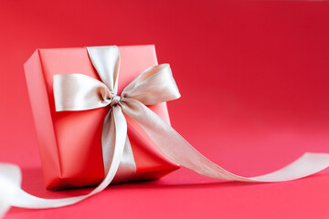 Red gift box with bow on red background. Happy Birthday or Valentine's Day concept.