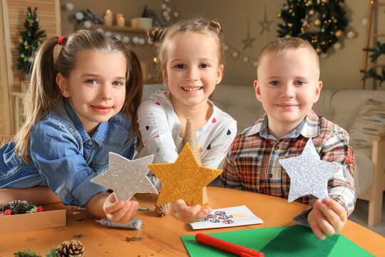 Cute little children with beautiful stars at home. Making Christmas decor