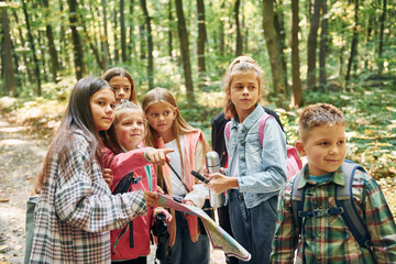 Fototapeta premium Front view. Kids in green forest at summer daytime together