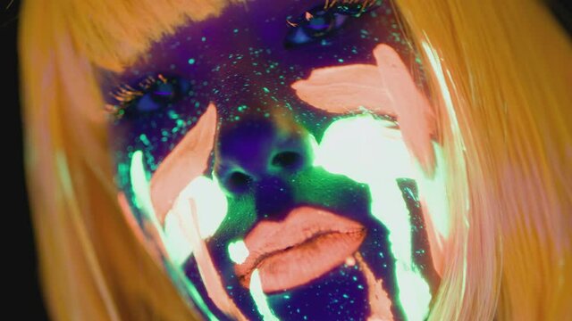 Close up portrait of young woman with bright fluorescent makeup in orange wig dancing to camera