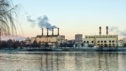 Fototapeta na wymiar Industrial air pollution. Winter landscape with factory and trees. The concept of environmental pollution.