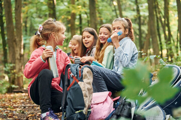 Sitting and having a rest. Kids in green forest at summer daytime together