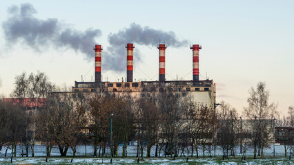 Fototapeta na wymiar Industrial air pollution. Winter landscape with factory and trees. The concept of environmental pollution.