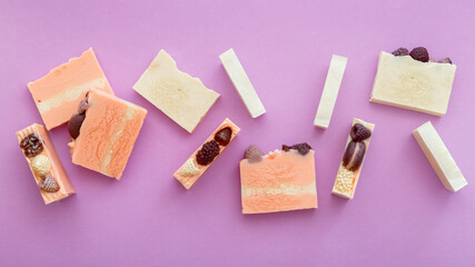 Natural handmade soap bars flat lay composition. Many fragrant handmade spa organic pink white soap bars. Homemade beauty products on purple background. Top view. Long web banner.