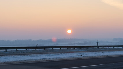 Winter landscape in snow nature with sun, field and trees. Magical winter sunset in a snow field.
