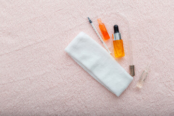Cosmetics and beautician tools. Darsonval cosmetology device for face, hair and body skin care. Serum oil ampoules and syringes for youth beauty injections on pink towel with copy space.