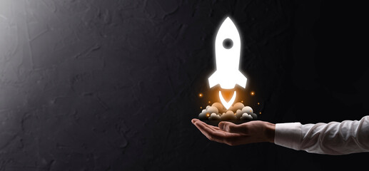Startup business concept, Businessman holding tablet and icon rocket is launching and soar flying out from screen with network connection on dark background.
