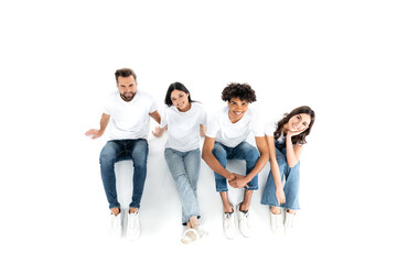 Fototapeta premium top view of happy multiethnic friends looking at camera while sitting on white.