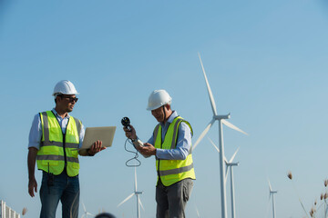 Two engineers working and holding wind measurement on wind turbine farm Power Generator Station on...