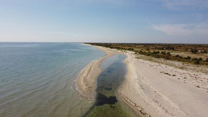 Aerial view of sandy beach and Black sea. Coastline with green bushes and grass. Dzharylhach island, Ukraine