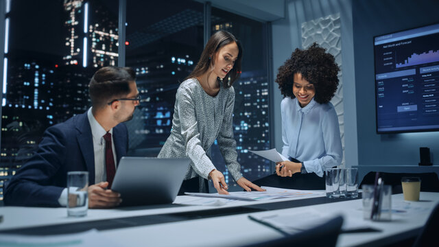 Office Conference Room Meeting: Diverse Team of Top Managers Talk, Brainstorm, Use Laptop Computer. Business Partners Discuss Financial Reports, Plan Operations Based on Line and Pie Graph Reports. - Powered by Adobe