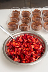 Pastry chef preparing step by step delicious dessert black forest or chip with chocolate biscuit, cream and fresh strawberries in shot glasses