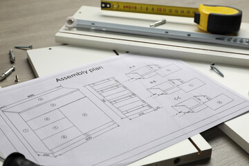 White furniture assembly parts, plan and tools on wooden table