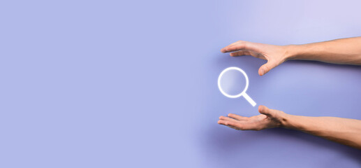 Male hand holding magnifying glass ,search icon on blue background. Concept search engine optimization, customer support.Browsing Internet Data Information.Networking Concept.