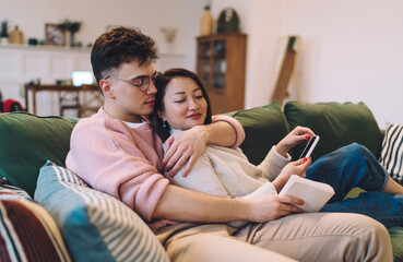 Caucasian man hugging asian woman on sofa at home