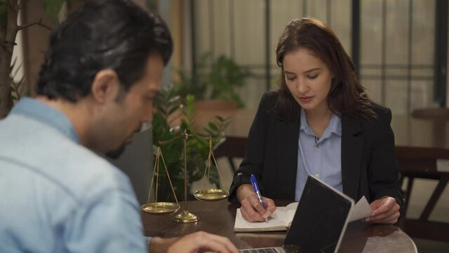 couple talking and working with laptop computer together in office.  business woman take note from discussion with customer. lawyer Write a message from a conversation with a client.