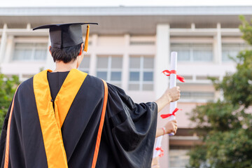 The graduates raised their hands to celebrate graduation with a certificate in hand and her...