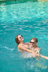 Young couple swimming in a pool and feeling excited