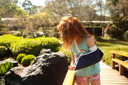 Girl with a broken arm looking over a bridge