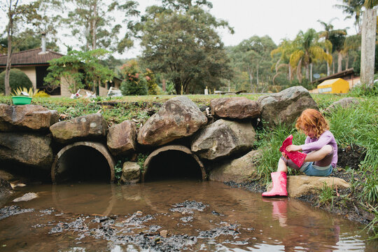 Girl exploring a stormwater drain in gumboots