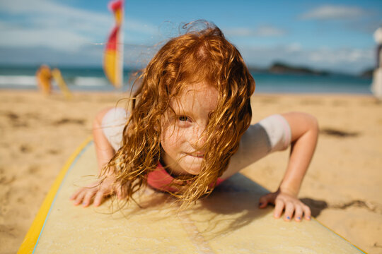 Young girl laying on a surfboard at the beach