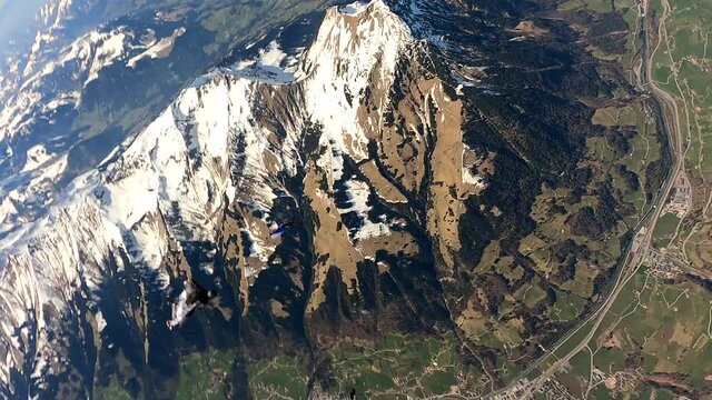 Skydiver in freefall above green mountainous landscape