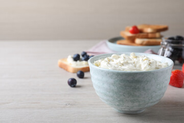 Tasty cream cheese and fresh berries on white wooden table. Space for text