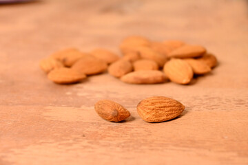closeup the bunch brown almond nuts over out of focus brown background.