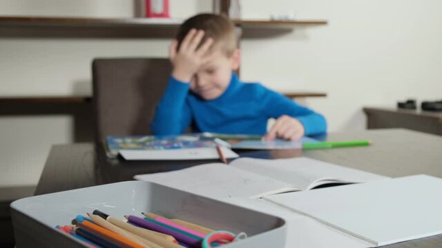 boy makes a mistake during homework. He gets upset and hits himself on the head. Distance learning online education. 