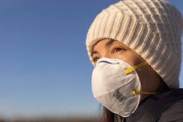 N95 face mask Asian woman wearing mouth covering outside during coronavirus pandemic.