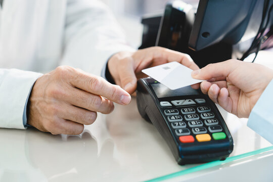 Closeup cropped image of e-commerce e-banking cashless wireless payment with credit card at drugstore pharmacy at cash point desk, buying medicines, drugs, pills