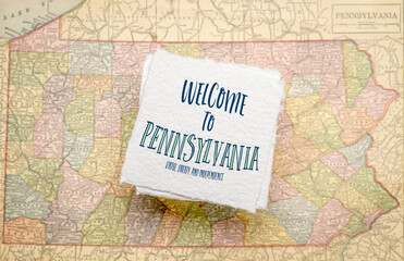 Welcome to Pennsylvania handwriting on a handmade paper against defocused vintage map