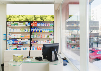 Empty spacious new modern cash point desk without visitors clients staff at pharmacy drugstore chemist`s store with shelves full of medicines