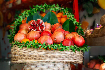 Fototapeta na wymiar Basket with juicy ripe pomegranate fruits and oranges prepared for squeezing juice in a street cafe